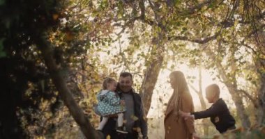 Aile sonbahar parkında eğlenir, yaprakları kusar, birlikte iyi vakit geçirir..