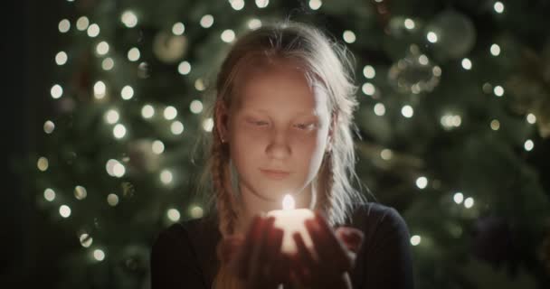 Child Holds Burning Candle His Hands Backdrop Blurry Christmas Tree — Stock Video