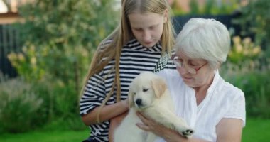 Torunuyla yaşlı bir bayan ve evin arka bahçesinde sevimli bir köpek yavrusu..