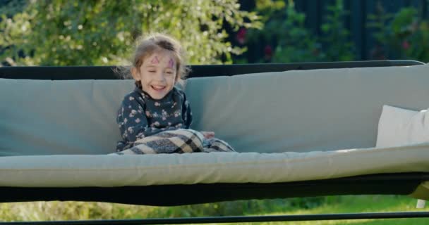 一个在花园里荡秋千的房子后院里 脸上挂着彩绘的可爱女孩的画像 — 图库视频影像