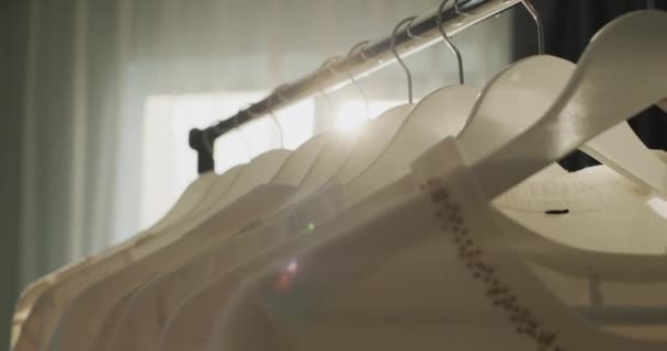 Regal Mit Kleiderbügeln Aus Weißer Kleidung Den Sonnenstrahlen Aus Dem — Stockvideo