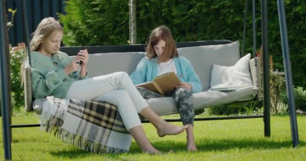 Dois Amigos Estão Relaxando Balanço Jardim Uma Rapariga Usa Smartphone — Vídeo de Stock