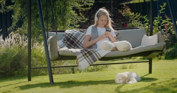 Una Adolescente Está Descansando Columpio Del Jardín Usando Teléfono Inteligente — Vídeos de Stock