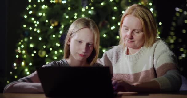 Anne Kızı Birlikte Dizüstü Bilgisayara Bakıyorlar Noel Ağacının Bulanık Işıklarının — Stok video