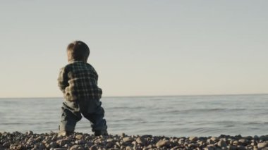 İki yıllık kasıtlı bir çocuk denize bir taş atar.