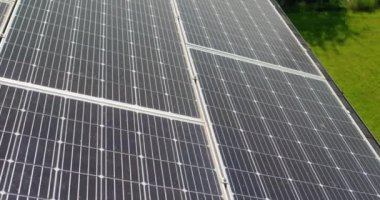 Kulübenin çatısındaki güneş panelleri. Panellerden evin arka bahçesindeki yeşil çimlere kamera yansıması.