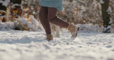 Köpeğiyle karda koşan, kış ormanında yürüyüş yapan bir kadın. 4k ağır çekim videosu