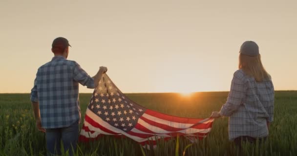 夕阳西下时 两个快乐的农民在麦田上升起美国国旗 7月4日 美国独立日的概念 — 图库视频影像