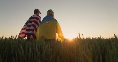 Buğday tarlasında Amerika ve Ukrayna bayraklı genç bir çift.