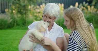 Torunuyla yaşlı bir bayan ve evin arka bahçesinde sevimli bir köpek yavrusu..
