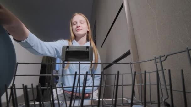 Neşeli Genç Bir Kız Bulaşık Makinesine Köpeğinin Yanına Tabak Koyar — Stok video