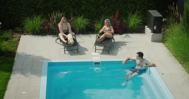 一个喝鸡尾酒的男人正在游泳池里放松 旁边是两个漂亮的女人 梦幻假期 — 图库视频影像
