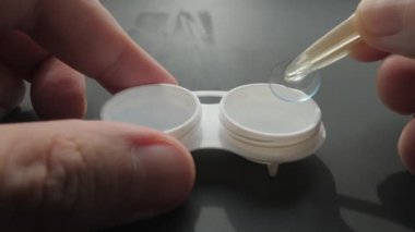 Elinde cımbız olan kontakt lens kutusuna yakın çekim.