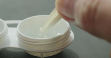 Cımbız kullanarak lens kullanan biriyle kontak lens kutusunun makro görünümü.