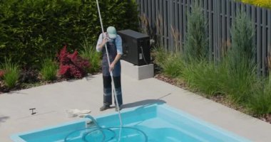 Bir işçi yüzme havuzunu özel bir elektrikli süpürgeyle temizler..