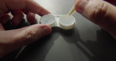 Elinde cımbız olan kontakt lens kutusuna yakın çekim.
