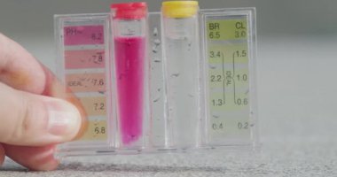 Bir el, PH ve klor seviyeleri için test tüpü tutar.