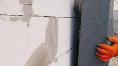 İşçi, evin duvarına yalıtım malzemesi yapıştırıyor..