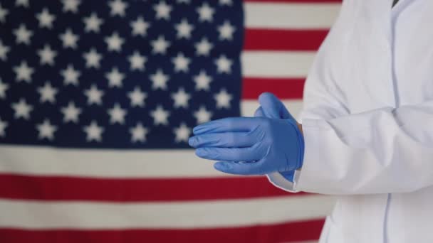 ドクターの側面のビューはアメリカの旗に対する保護手袋を身に着けています — ストック動画