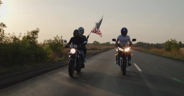 自転車のグループは 国中を旅するアメリカの旗と 日没時に高速道路に沿って乗っています — ストック動画