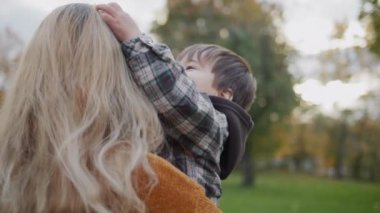 Mom and son are walking in the autumn park.