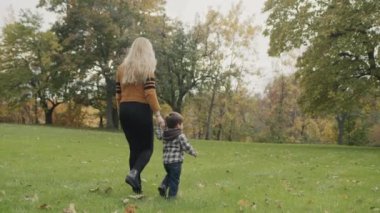 Mom and son are walking in the autumn park.
