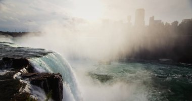 Niagara Şelalesi 'nin muhteşem manzarası. Sis duvarı Kanada kıyılarını kaplıyor. Nehrin çok altında bir tekne yüzüyor..