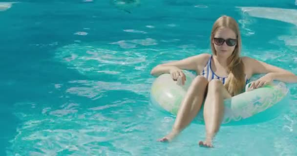一个少女在游泳池表面上的一个充气圆圈中漂浮着 — 图库视频影像