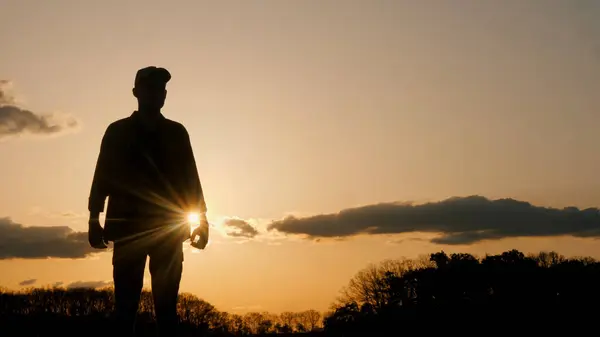 カラフルな空と雲に囲まれた素晴らしい日没の前に平和に立つ男のシルエットは 自然と調和した楽しいジェスチャーを披露します ロイヤリティフリーのストック画像