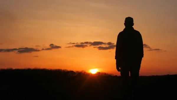 Ein Mann Silhouette Ist Gegen Den Roten Himmel Bei Sonnenuntergang lizenzfreie Stockbilder