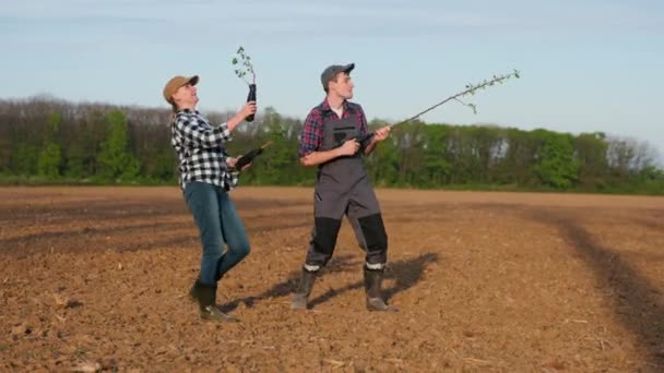 二人の農民は ロックミュージシャンを模倣して 苗で精力的に踊ります — ストック動画