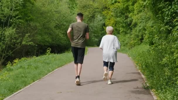 Starsza Kobieta Młodym Mężczyzną Biegającym Parku Koncepcja Seniorów Widok Tyłu — Wideo stockowe