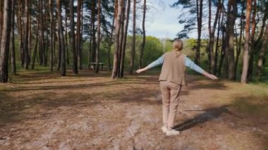 Orta yaşlı bir kadın çam ormanında yürümekten zevk alıyor..