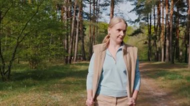 Çam ormanı manzarasında gezinen orta yaşlı bir kadın.