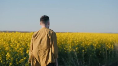 Genç bir çiftçi kolza tohumu tarlası boyunca yürür..