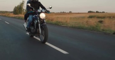 Genç bir çift, otoyolda motosiklet sürüyor, çerçevede görünen yüzler yok..