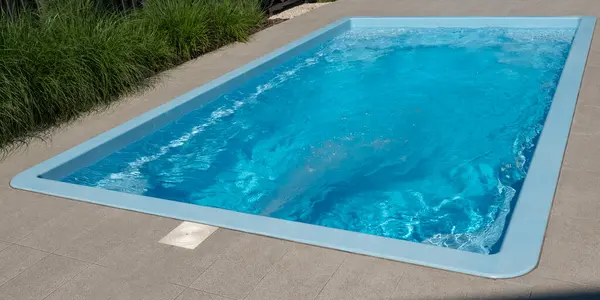 stock image A backyard swimming pool features a counter-current system, creating a steady water flow that allows for continuous swimming. This setup is perfect for those looking to exercise or enjoy a swim