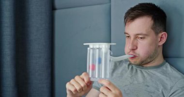 Genç bir adam akciğer fonksiyonlarını değerlendirmek için spirometre kullanırken görülüyor. Bu tıbbi cihaz nefes alıp verebileceği hava miktarını ölçerek solunum sağlığı hakkında hayati veriler sağlıyor. Şey...
