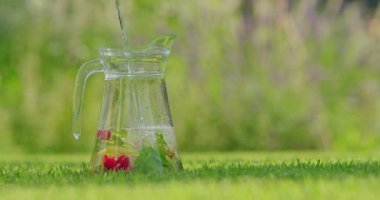 Taze meyvelerle dolu bir sürahiye taze meyve suyu dökülerek sıcak bir yaz gününde doğal limonata oluşturuluyor. Meyve ve suyunun canlı renkleri birleşerek...