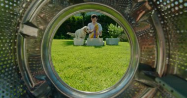 Arka bahçede, genç bir adam çamaşırları düzenliyor, ve komik bir köpek ona yardım etmeye çalışıyor. Adam gülüyor ve köpek maskaralıkları neşeli ve neşeli bir atmosfer yaratıyor, mutluluğu yakalıyor.