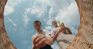 Bir sepetin içinden genç bir adam ve kız kardeşi içine mısır kulakları yerleştirir. Perspektif, hasat sürecini ve hasat sürecini vurgulayarak, kardeşlerin ellerini ve altın mısırı yakalıyor.