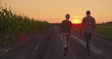 Arkadan bir erkek ve dişi çiftçi, mısır tarlasıyla kaplı bir köy yolunda yürürken görülüyor. Batan güneş, sohbete dalarken sahnenin üzerinde sıcak, altın bir parıltı saçar. Bu huzur