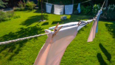 Pastel renkli yastık kılıflarının yakın plan çekimi bir çamaşır ipine bağlanmış, rüzgarda hafifçe sallanıyordu. Canlı yeşil çimenler ve sakin arka bahçe, sükuneti vurgulayarak, fevkalade bir arka plan sağlar