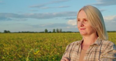 Orta yaşlı bir çiftçi kadın gün batımında yemyeşil bir tarlanın ortasında güven içinde duruyor. Uzağa dikkatlice bakarken kolları çapraz. Sıkı çalışmayı ve bağlılığı temsil ediyor.