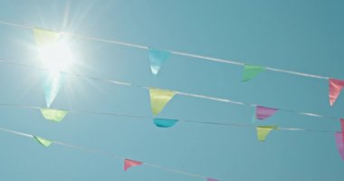 Mavi, sarı ve yeşil tonlarda parlak flamalar, parlak mavi bir gökyüzüne asılır, güneş ışığı içinden akar, neşeli ve neşeli bir atmosfer yaratır. Gökyüzü açık ve...