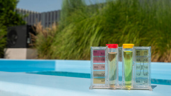 Подробный обзор комплекта для тестирования воды в бассейне с прозрачными трубками, наполненными цветными жидкостями, указывающими на уровень рН и хлора. Расположенный на стороне бассейна, акцент сделан на четких показаниях