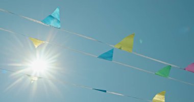 Mavi, sarı ve yeşil tonlarda parlak flamalar, parlak mavi bir gökyüzüne asılır, güneş ışığı içinden akar, neşeli ve neşeli bir atmosfer yaratır. Gökyüzü açık ve...