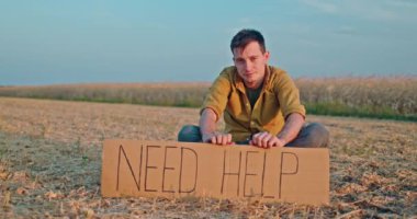 Genç bir çiftçi uçsuz bucaksız bir tarlada tek başına oturuyor. Elinde 