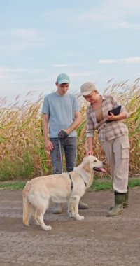 Bir çiftçi çift, köpekleriyle birlikte olgun sarı mısır tarlasının yanında dururlar. Sahne, çiftlik hayatının sıcaklığını ve basitliğini simgeliyor. Altın mısır tarlası da arka planda. Şey...