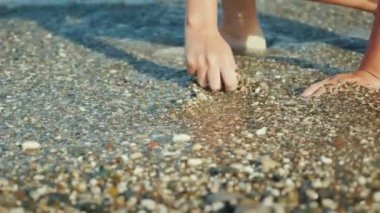 Bir kadının el sığ çakıl deniz kenarında bir şey arıyor. 4k video